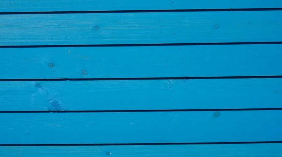 Head-to-Head: Coverage & Application - Close-up of vibrant blue wooden paneling with a detailed texture