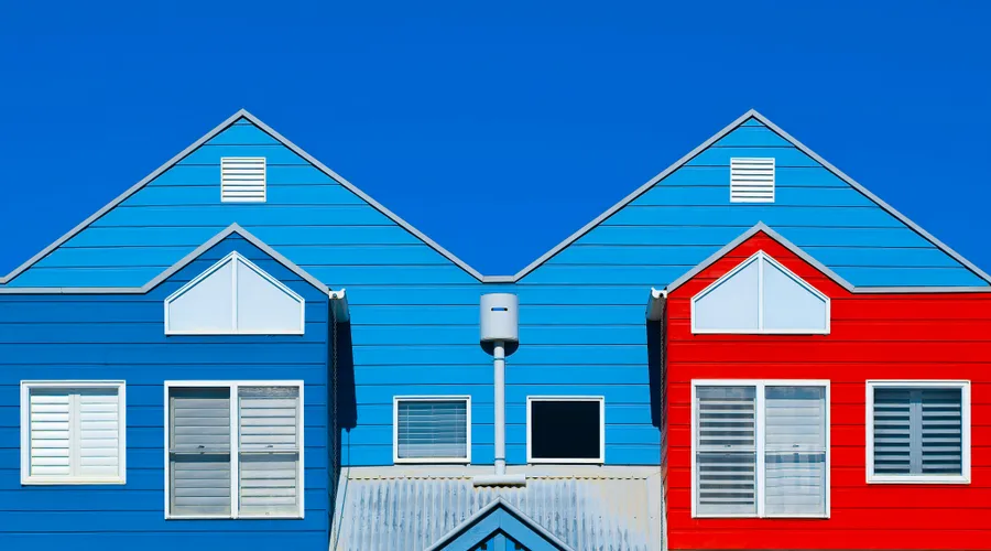 2. Sherwin-Williams - Brightly painted house facades in blue and red create a striking contrast against a clear blue sky
