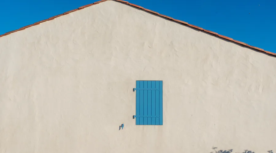 What Is Elastomeric Caulk? - Minimalist house wall with a blue shutter against a clear blue sky