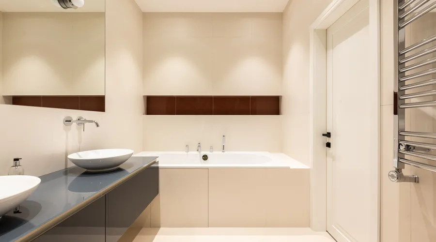 What Is Silicone-Acrylic Blend Caulk? - Interior of modern bathroom with sinks on cabinet near tap and mirror near bath and door
