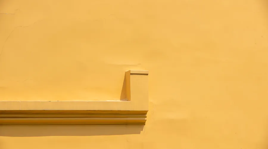 Head-to-Head: Stain Resistance - Abstract view of a minimalist yellow stucco wall with architectural detail