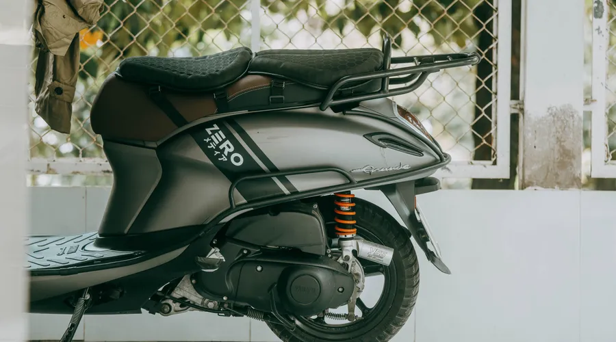 Head-to-Head: Aesthetic Options - A close-up view of a modern gray scooter parked indoors with a jacket hanging nearby