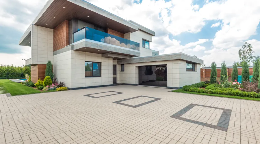What Are Garage Mats and Interlocking Tiles? - Elegant modern house exterior with lush greenery and ample driveway space