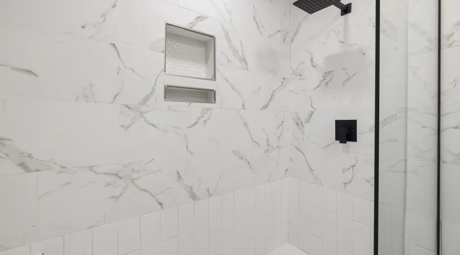 High-Gloss Finish - Sleek bathroom shower featuring marble tiles and black fixtures