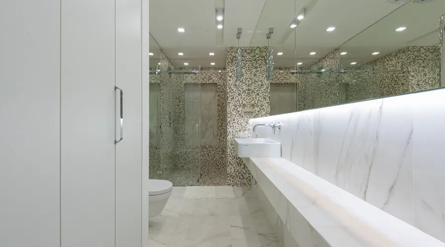 Walls vs Ceiling: Which Finish Where - Contemporary restroom with marble tile and toilet behind glass wall with sink under mirror