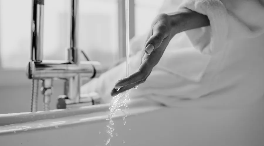 Pros of Same-Color Trim - Black and white photo of a hand under tap water in a stylish bathroom setting